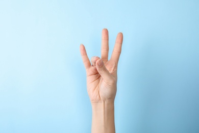Photo of Woman showing number seven on color background, closeup. Sign language