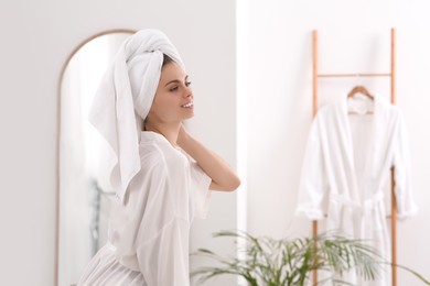 Photo of Beautiful woman wearing white robe in light bathroom