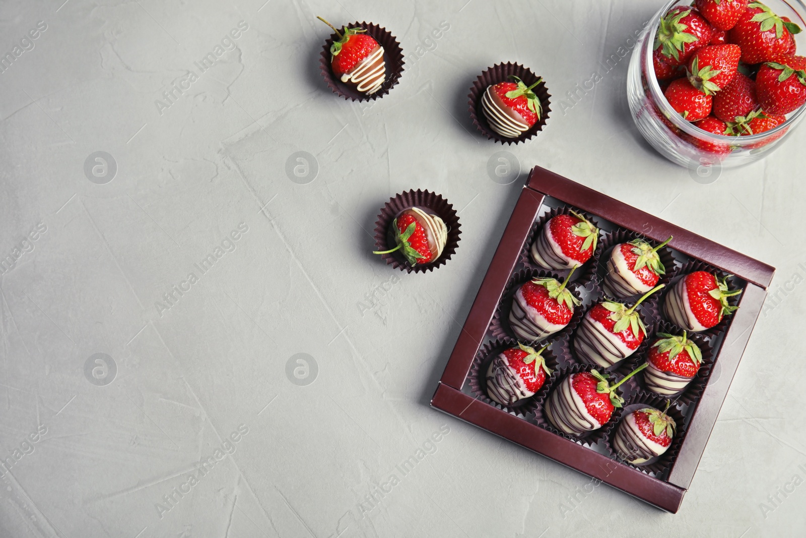 Photo of Flat lay composition with chocolate covered strawberries on grey background