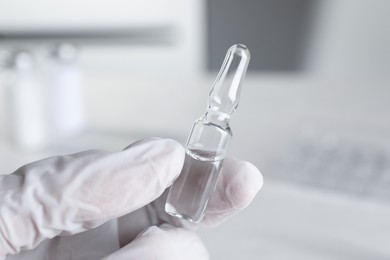 Photo of Doctor holding pharmaceutical ampoule with medication indoors, closeup