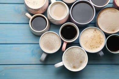 Many cups of different coffee drinks on light blue wooden table, flat lay