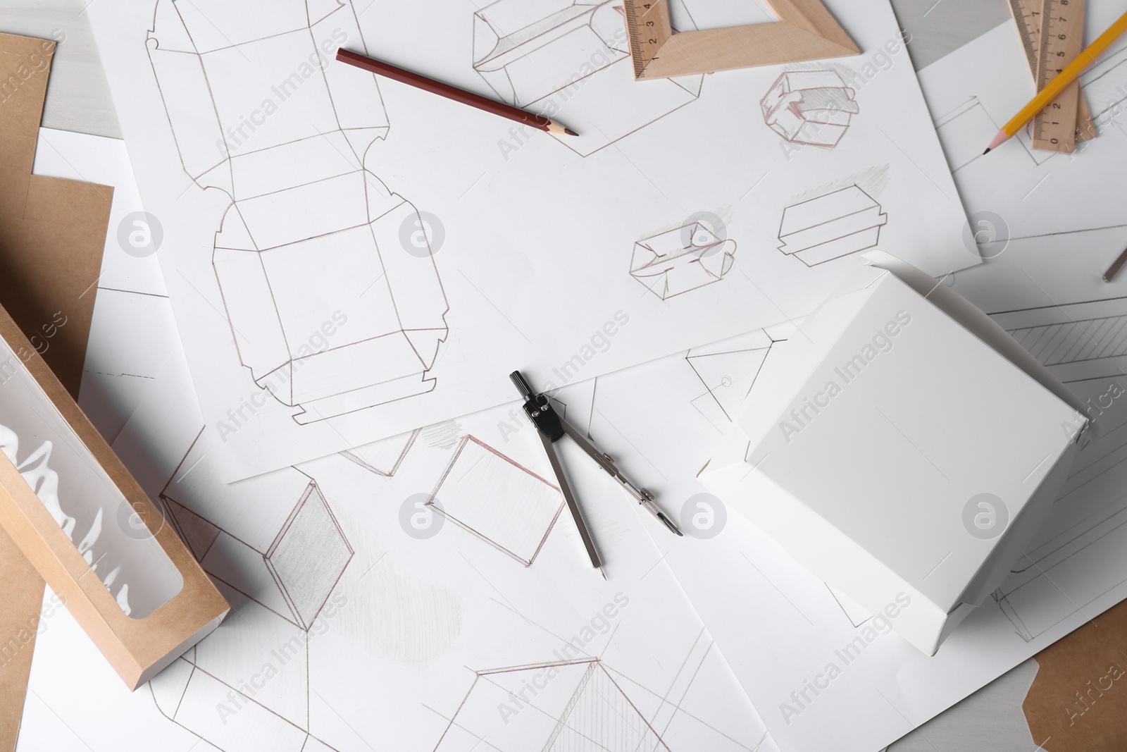 Photo of Creating packaging design. Drawings, boxes and stationery on light table, flat lay