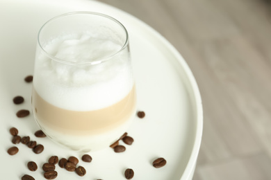 Photo of Delicious latte macchiato and coffee beans on white table, closeup