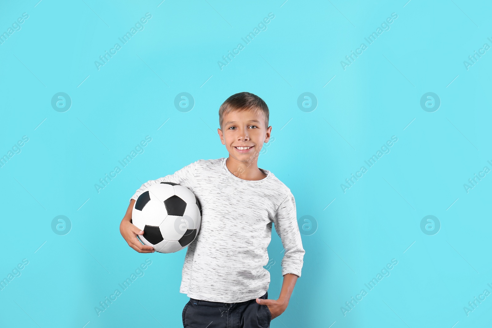 Photo of Adorable little boy with soccer ball on color background