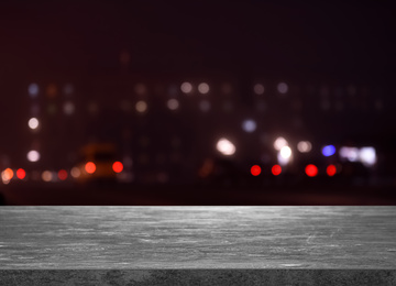 Image of Empty grey stone surface against blurred view of night city. Bokeh effect 