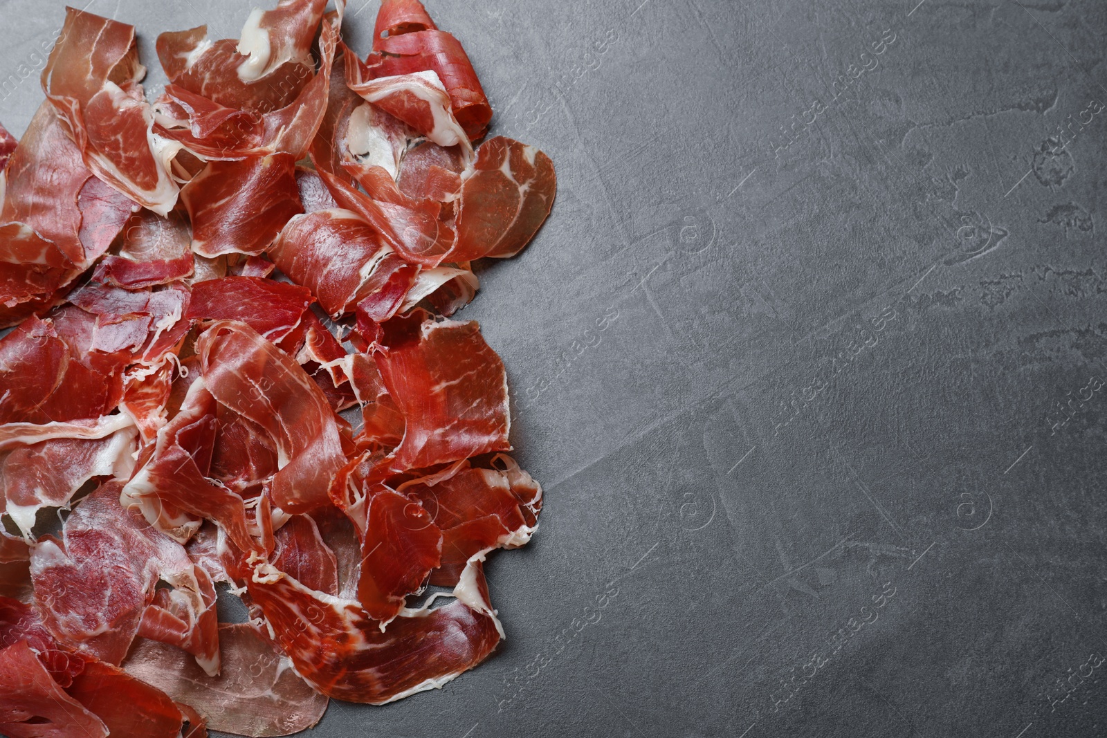 Photo of Tasty prosciutto on grey table, flat lay. Space for text