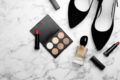 Flat lay composition with stylish shoes and cosmetics on white marble table