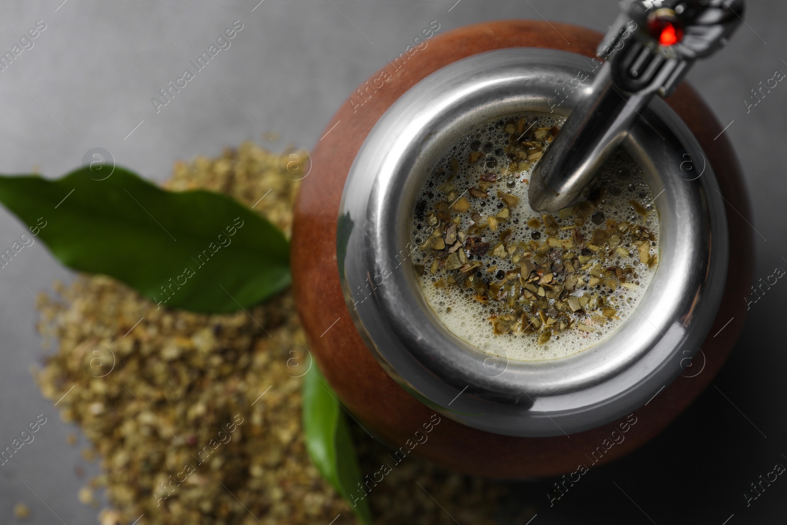 Photo of Calabash with mate tea and bombilla on light grey table, closeup. Space for text