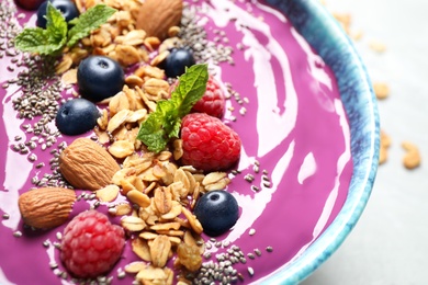 Delicious acai smoothie with granola and berries in dessert bowl on table, closeup