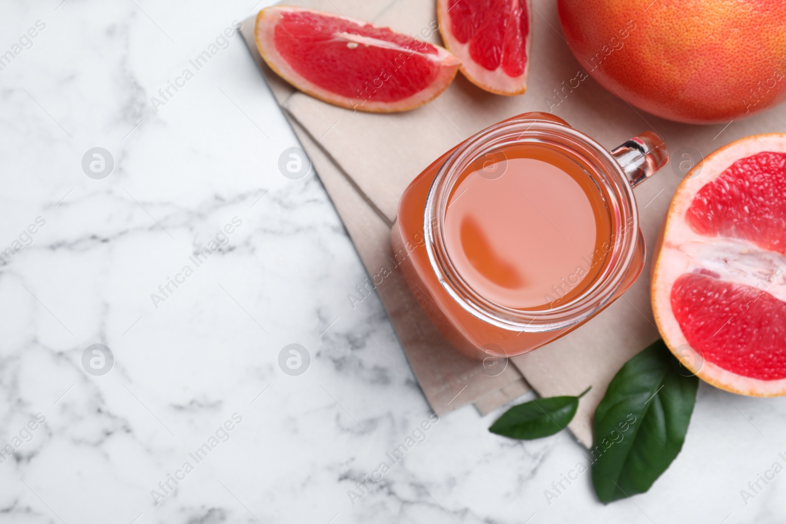 Photo of Tasty freshly made grapefruit juice and fruits on white marble table, flat lay. Space for text