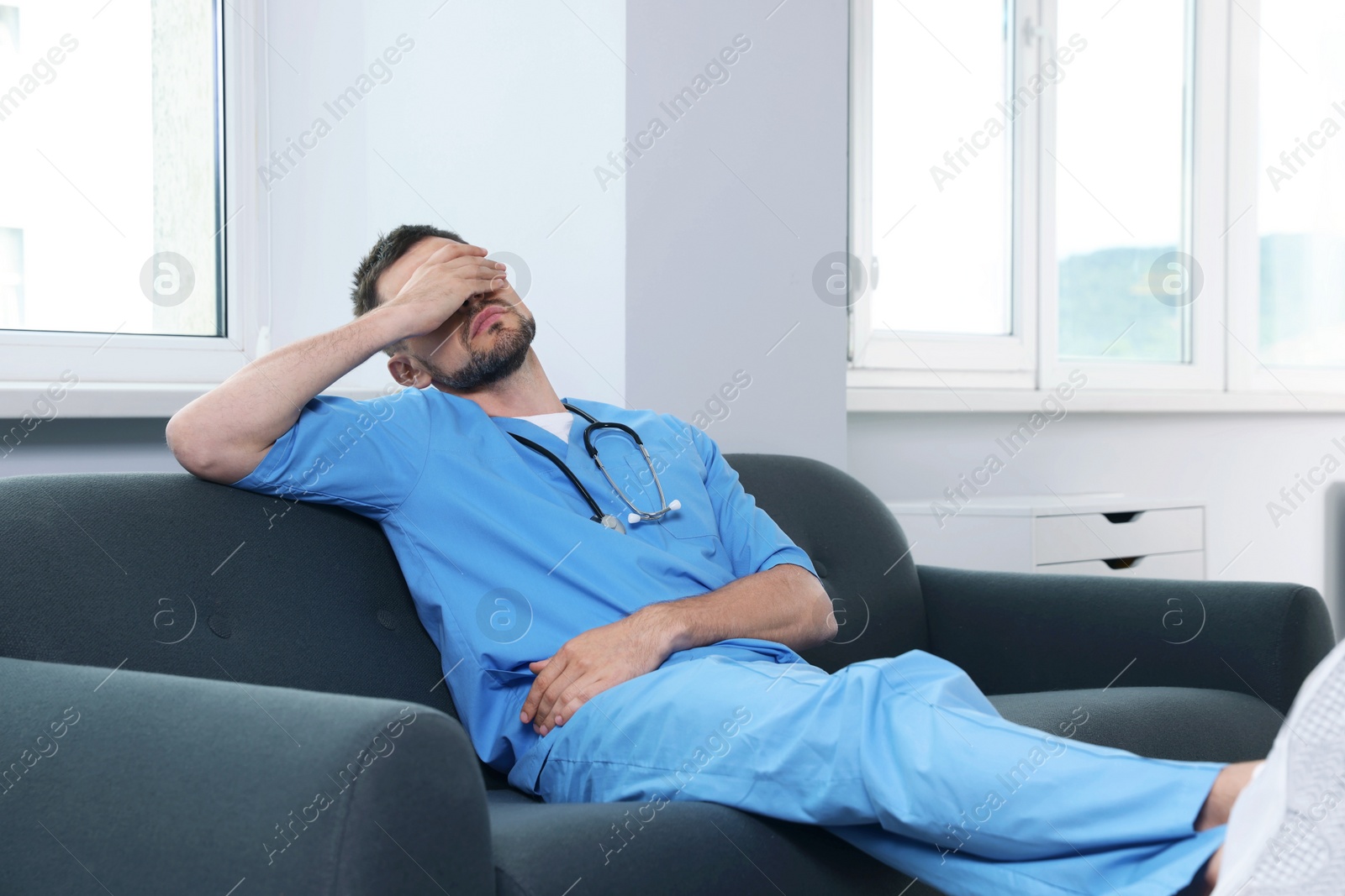 Photo of Exhausted doctor resting on sofa in hospital