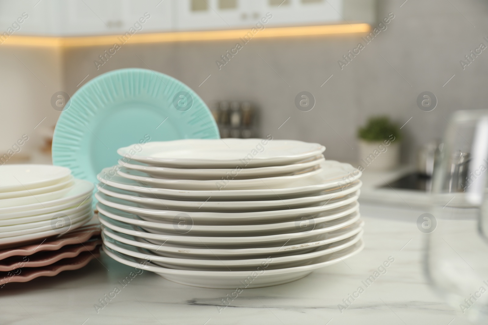 Photo of Clean plates on white marble table in kitchen