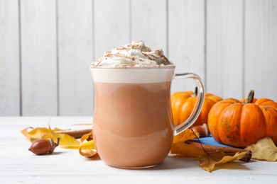 Photo of Delicious pumpkin latte on white table, closeup