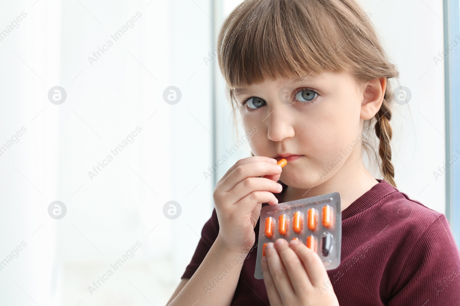 Photo of Little child taking pill indoors, space for text. Danger of medicament intoxication