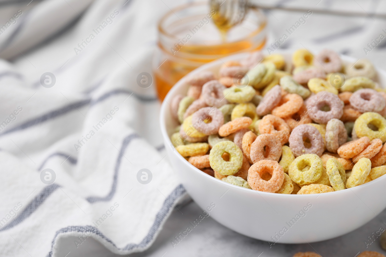 Photo of Tasty cereal rings in bowl on table, closeup. Space for text