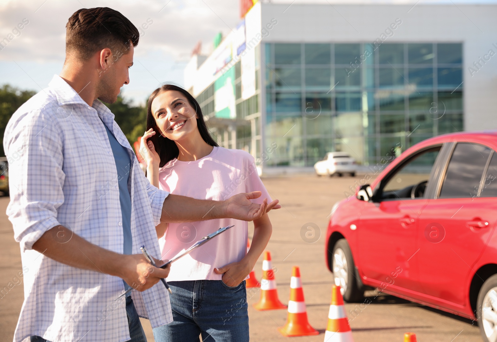 Photo of Instructor with clipboard and his student near car outdoors. Driving school exam