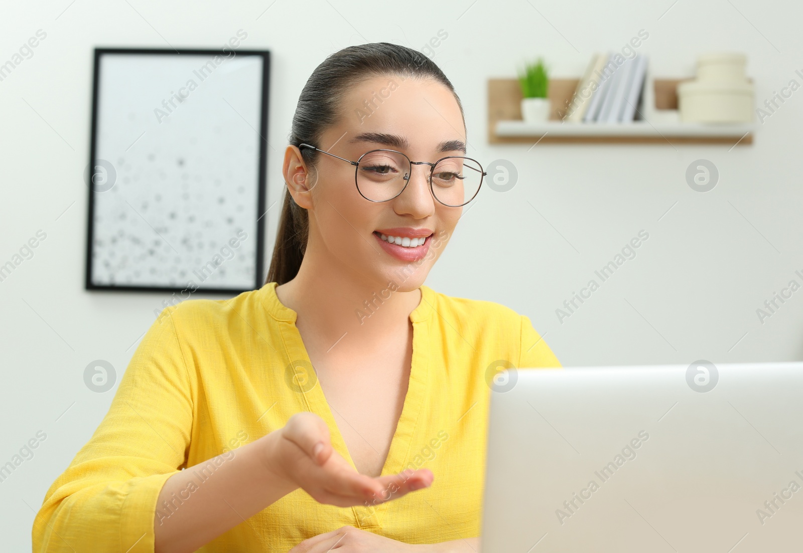 Photo of Home workplace. Happy woman talking by videochat on laptop in room