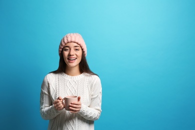 Photo of Young woman in sweater with cup of hot coffee on color background, space for text. Winter season