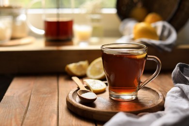 Photo of Glass cup with delicious tea, sugar and lemon on wooden table, space for text