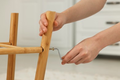Photo of Woman with hex key assembling furniture indoors, closeup