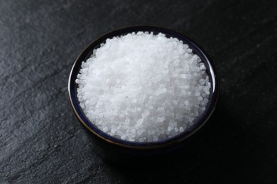 Photo of Organic white salt in bowl on black table