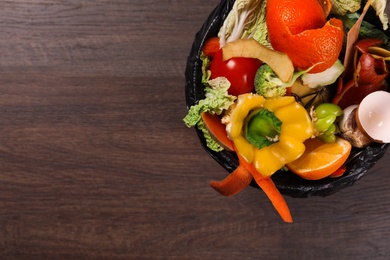 Photo of Natural garbage in trash bin on wooden background, top view with space for text. Composting of organic waste