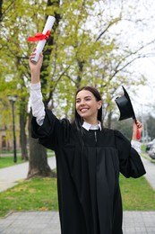 Happy student with diploma after graduation ceremony outdoors
