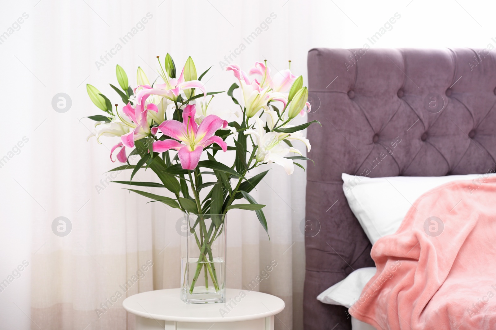 Photo of Vase with bouquet of beautiful lilies on table in bedroom. Space for text