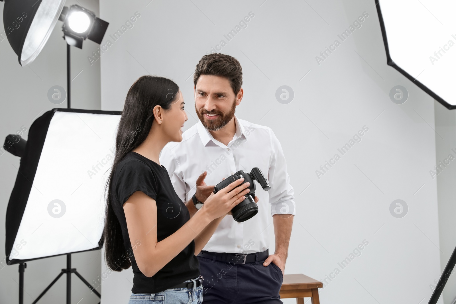 Photo of Professional photographer and model looking at pictures on camera in modern studio