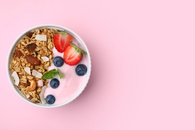 Photo of Tasty granola, yogurt and fresh berries in bowl on pink background, top view with space for text. Healthy breakfast