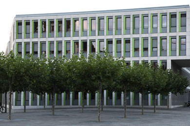 Photo of Beautiful view of modern building with big windows and trees outdoors