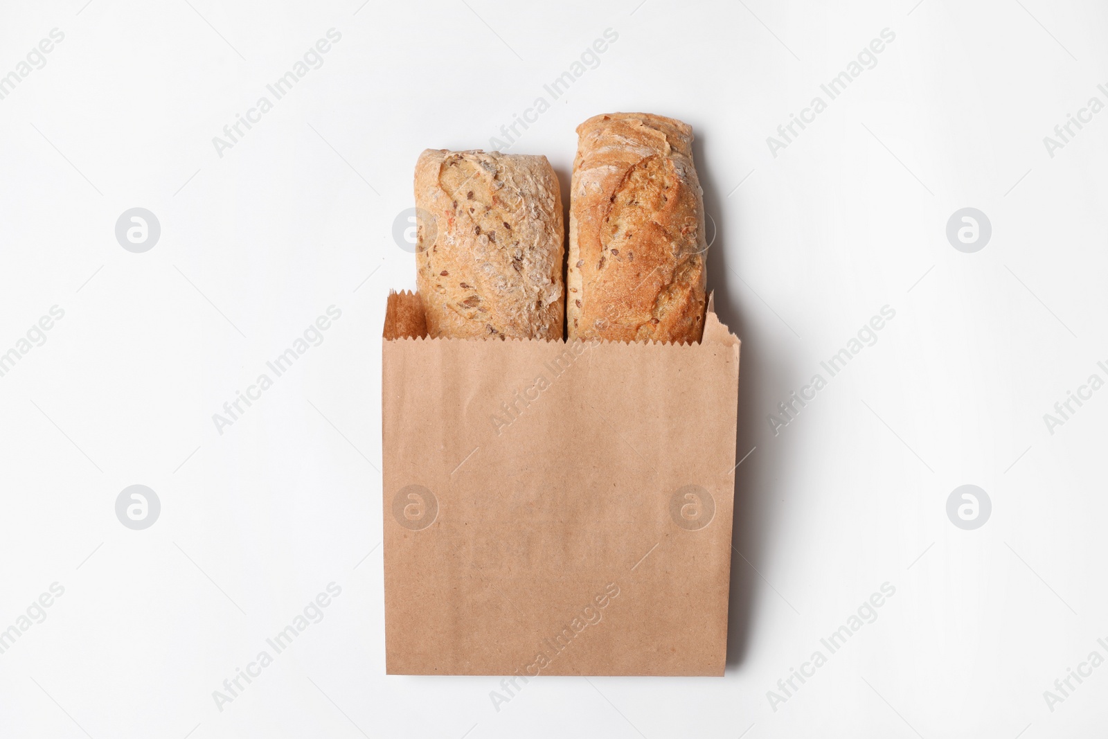 Photo of Paper bag with bread loaves on white background, top view. Space for design