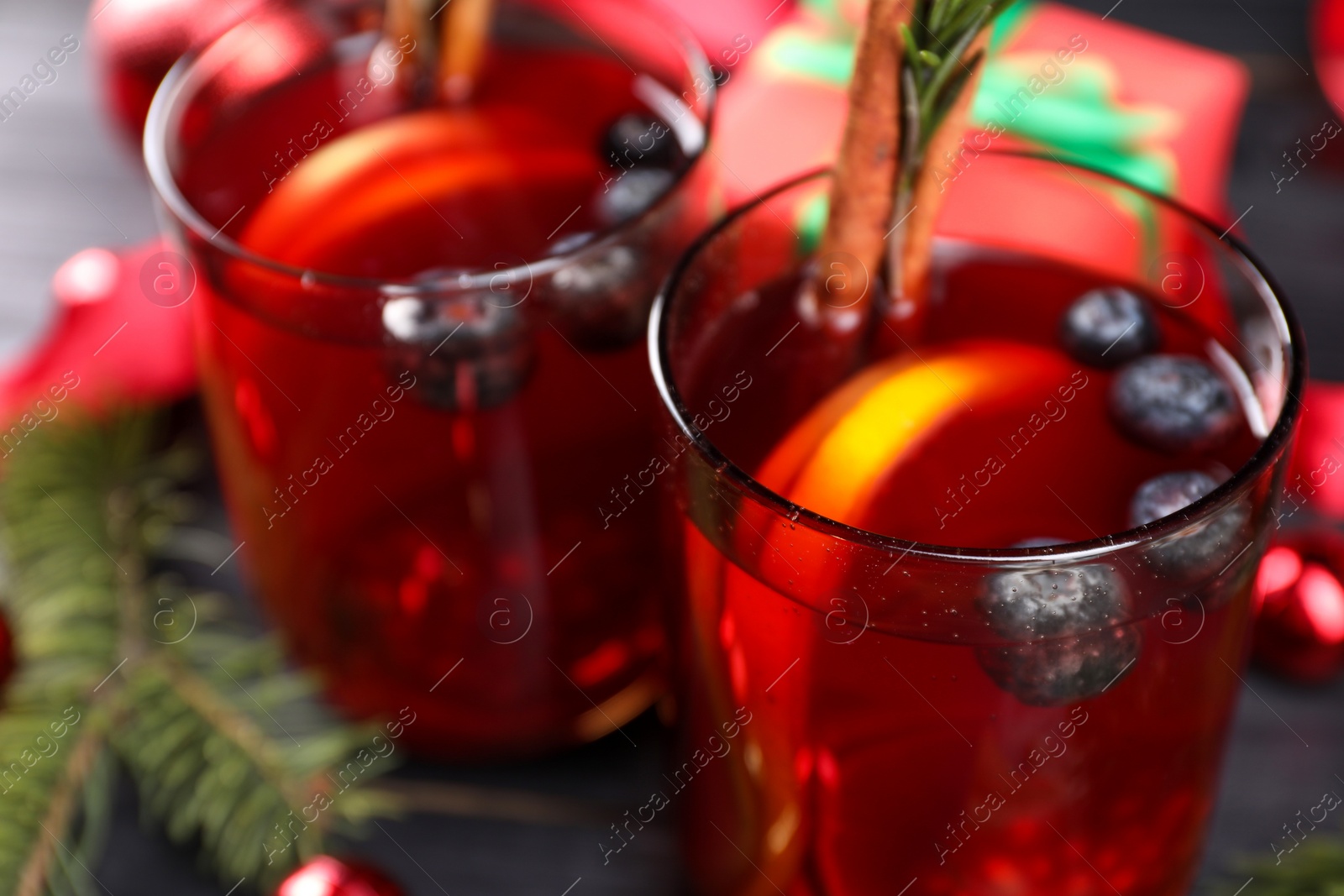 Photo of Aromatic Sangria drink in glasses, ingredients and Christmas decor on black wooden table, closeup