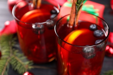 Aromatic Sangria drink in glasses, ingredients and Christmas decor on black wooden table, closeup