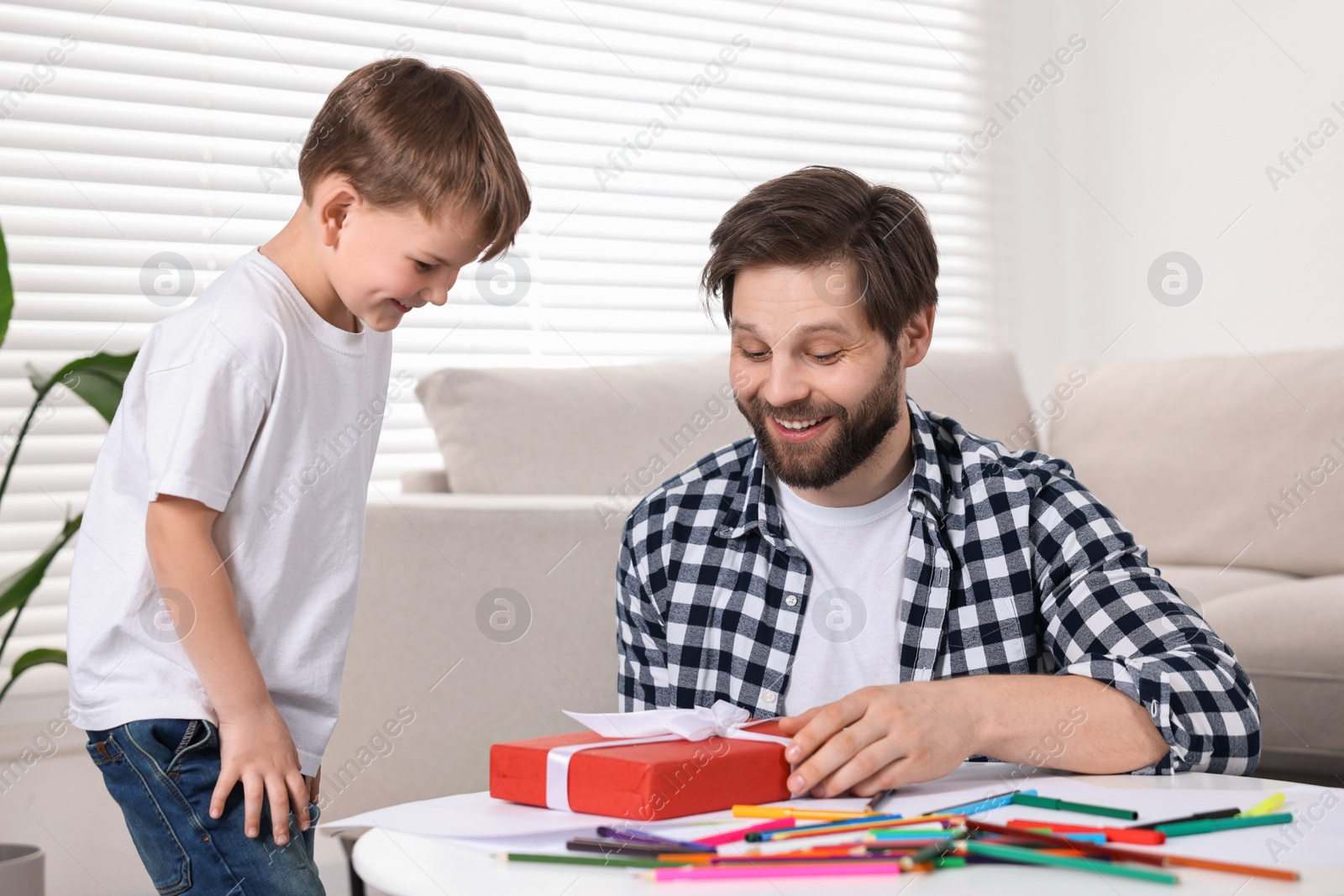 Photo of Happy dad receiving gift for Father's Day from his son at home