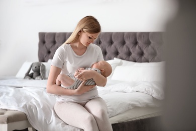 Photo of Young mother with her baby on bed at home
