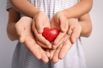 Photo of Family holding small red heart in hands together, closeup