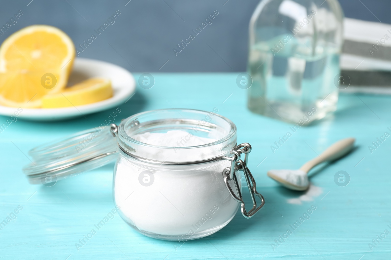 Photo of Baking soda in glass jar on light blue wooden table