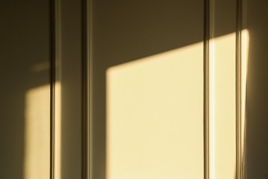 Light and shadow from window on beige wall indoors