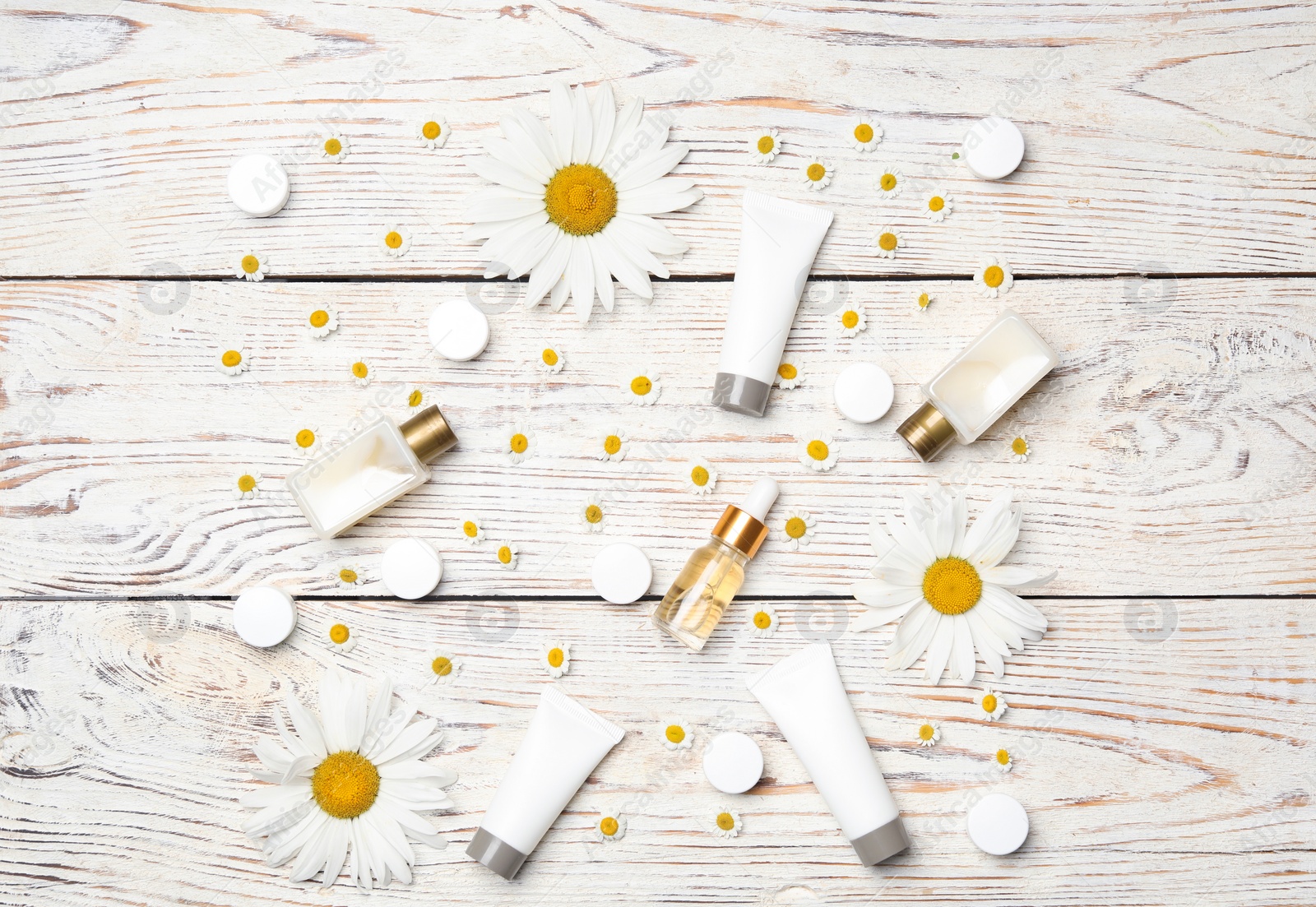 Photo of Flat lay composition with chamomile flowers and cosmetic products on white wooden table