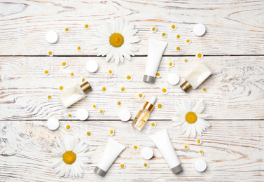 Photo of Flat lay composition with chamomile flowers and cosmetic products on white wooden table