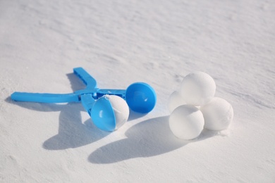 Photo of Snowballs and light blue plastic tool outdoors on winter day