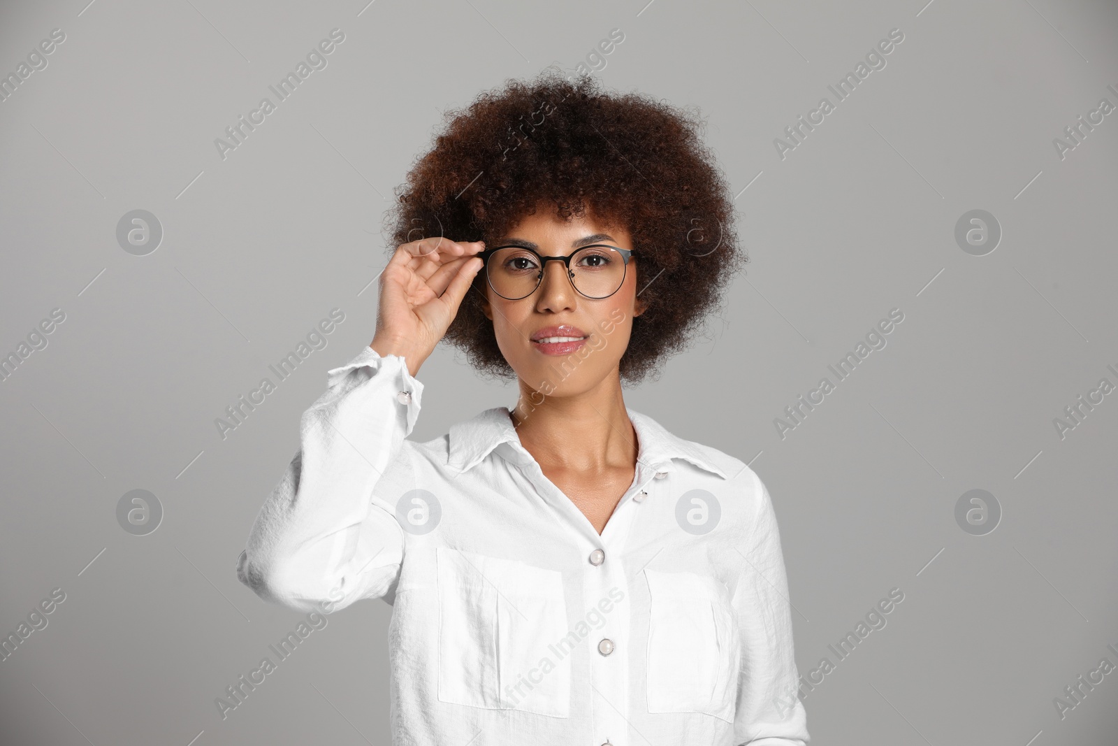 Photo of Beautiful young woman in eyeglasses on grey background