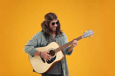 Photo of Stylish hippie man playing guitar on orange background