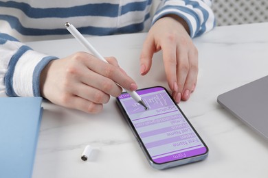 Electronic signature. Woman using stylus and mobile phone at white table, closeup