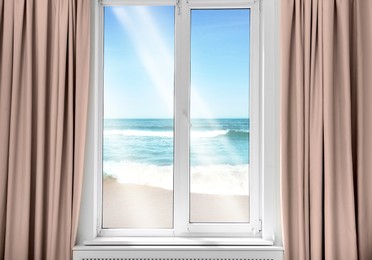 Beautiful view of sandy beach washed by sea on sunny day through window