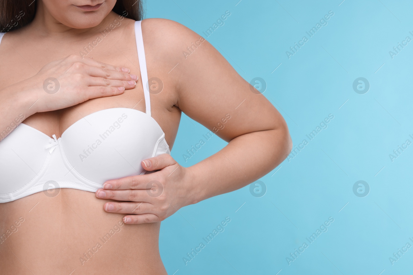 Photo of Mammology. Woman in bra doing breast self-examination on light blue background, closeup and space for text