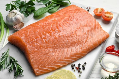 Photo of Fresh raw salmon and ingredients for marinade on white wooden table