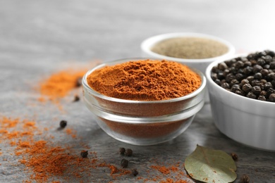 Bowls with different ground pepper and corns on grey table, closeup