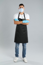 Photo of Waiter wearing medical face mask on light grey background